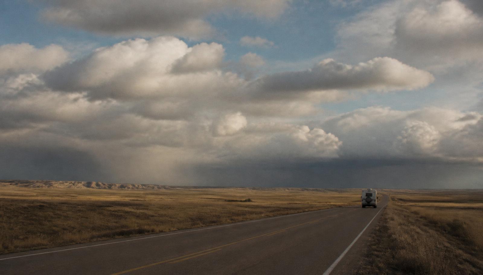A two-lane road crossing open plains under a vast sky